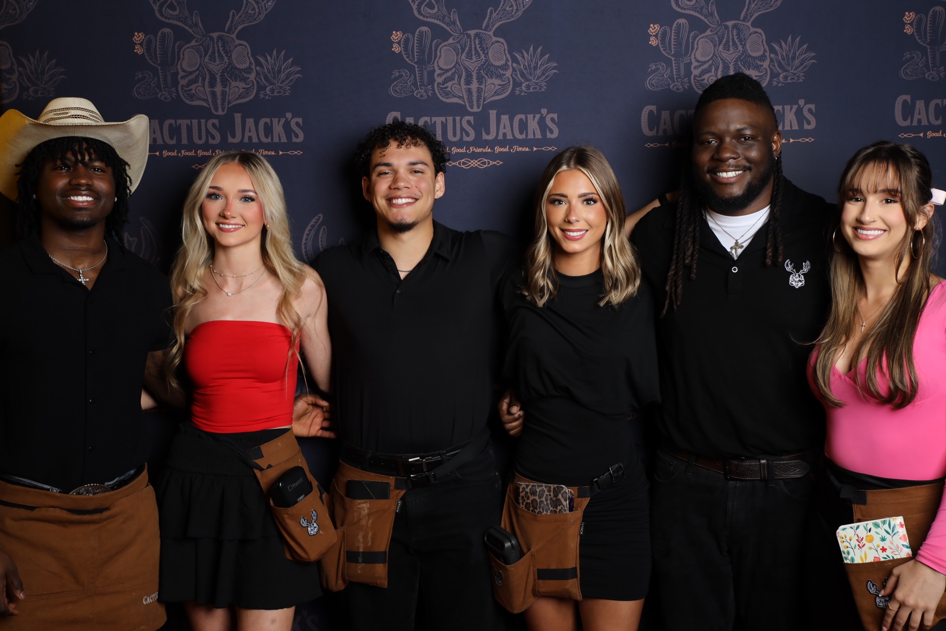 Group of guests posing at a Cactus Jack's branded photo booth backdrop