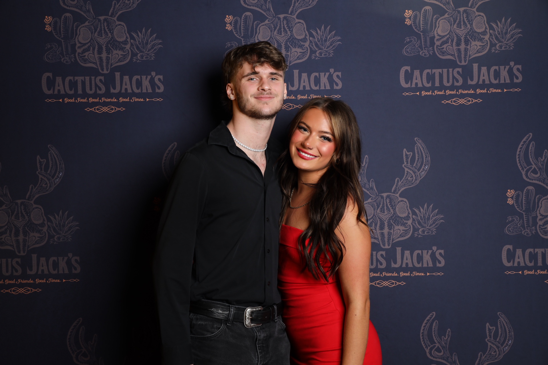 Couple posing at a Cactus Jack's branded photo booth backdrop