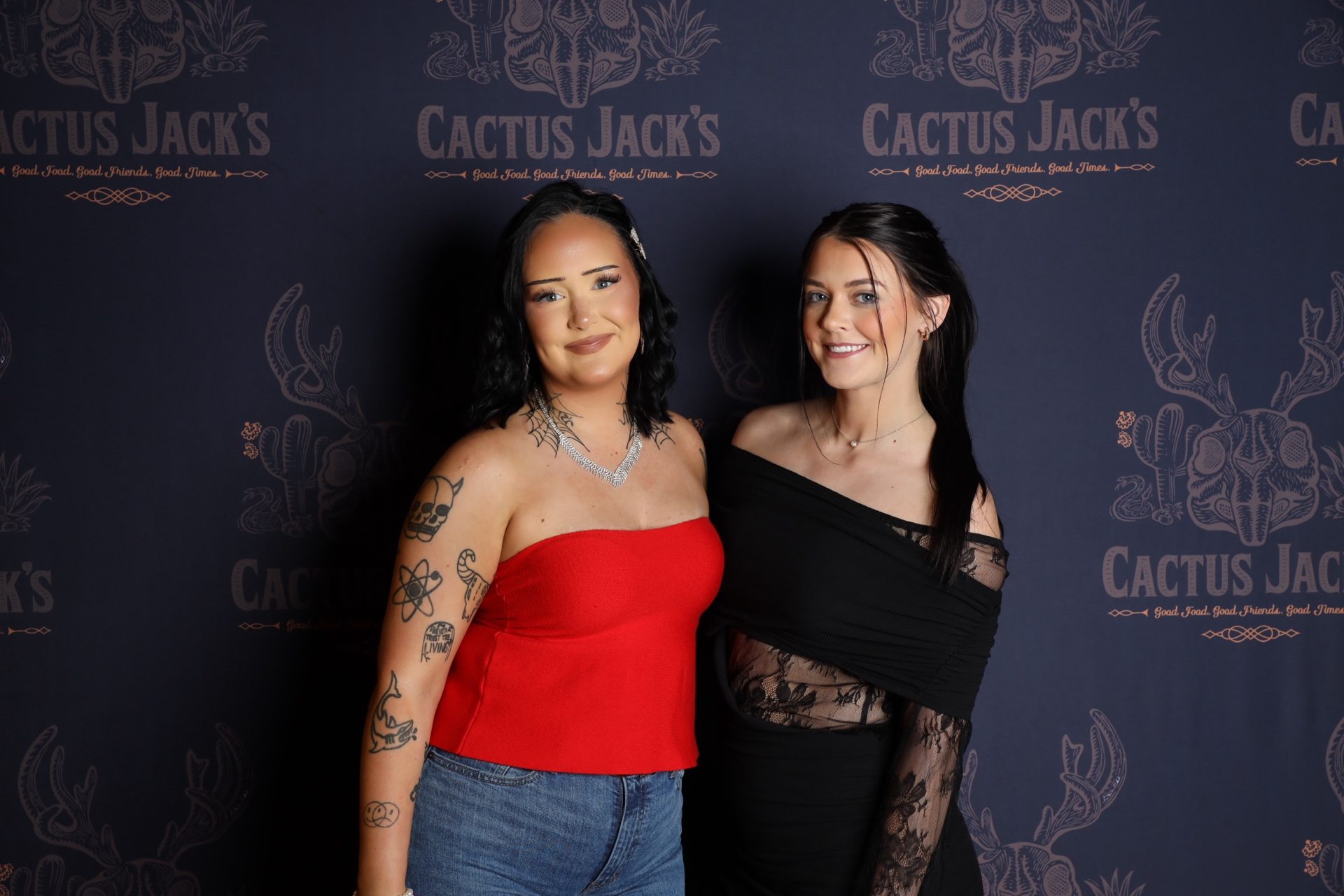 Two women posing at a Cactus Jack's photo booth backdrop